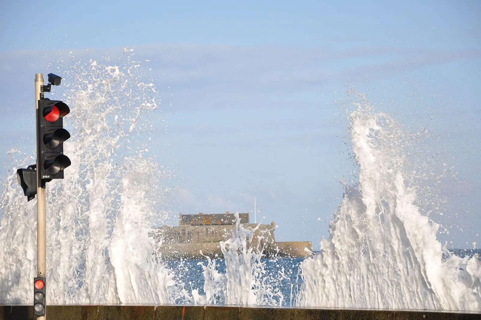 Gerbes d'eau au-dessus du muret du front de mer, Fort National en arrière-plan